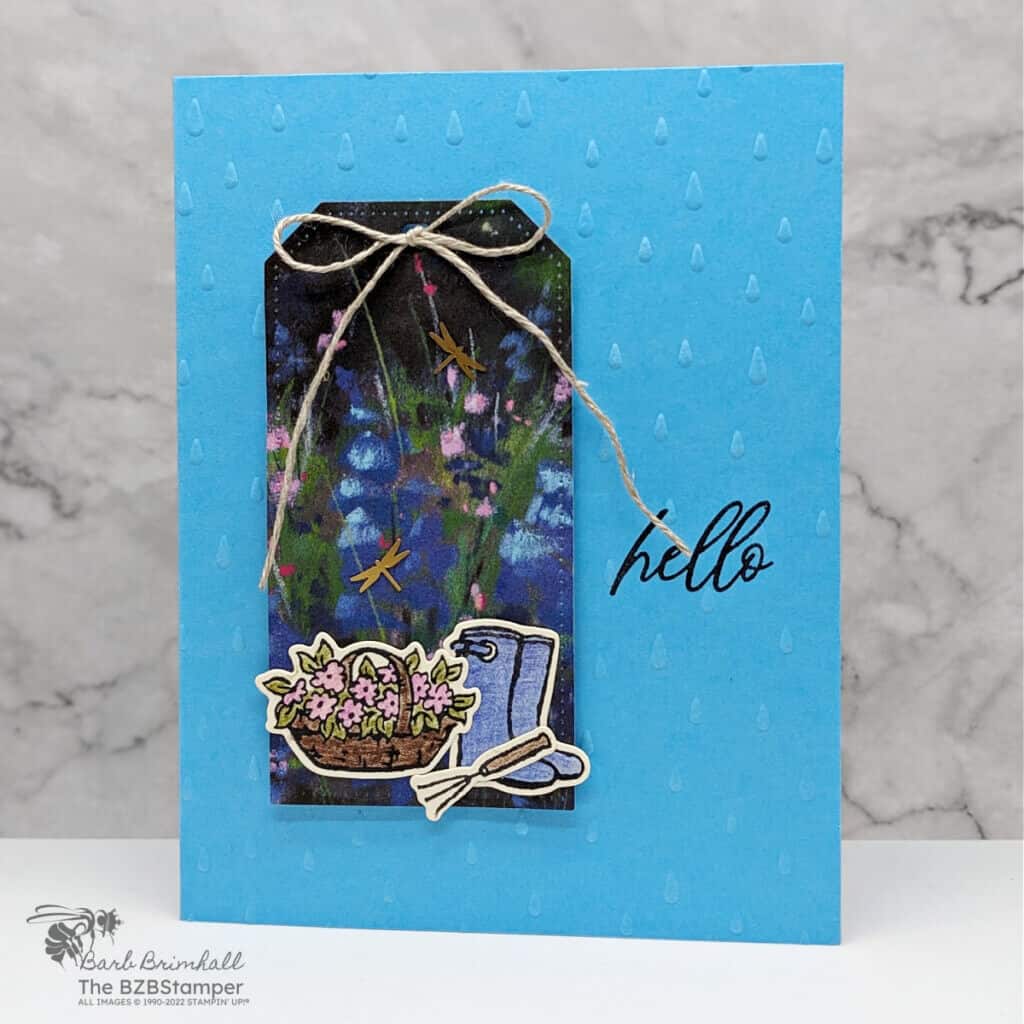 Garden Meadows Bundle from Stampin' Up! in different shades of blues and purples. Features a tag on the front of the card, with hello greeting and flowers, a gardening tool and rainboots.