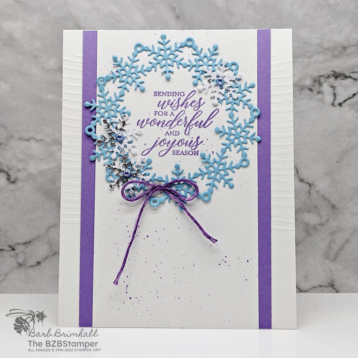 Christmas card in blues and purples featuring a wreath of snowflakes and a sentiment "sending wishes for a wondering and joyous season."