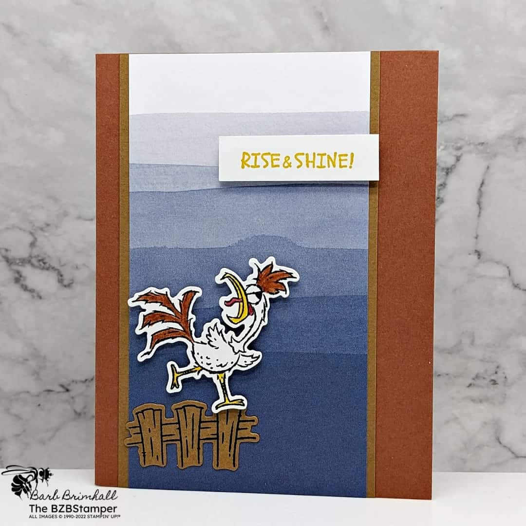 Card featuring a rooster on a fence in browns in blues with a "rise and shine" sentiment.