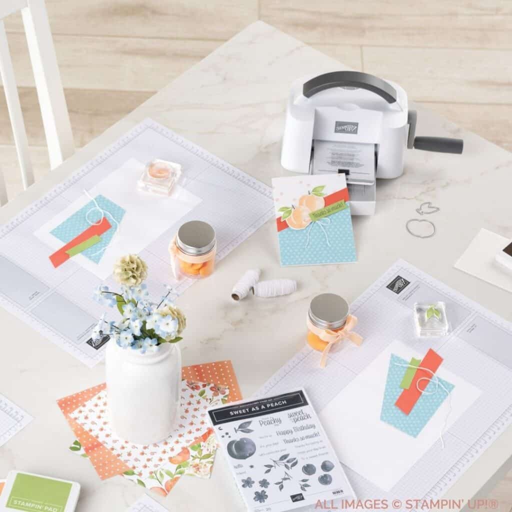15 Reasons Why It's Important To Craft with a picture of a stamp set, some ribbon, papercrafting supplies, a Cut & Emboss Machine  at a table in blues, greens and corals.