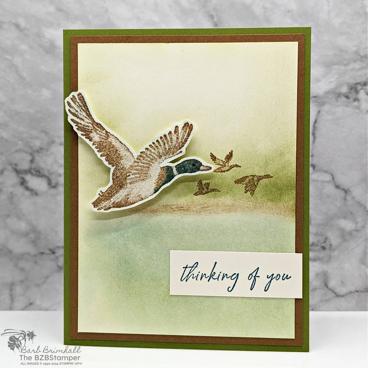 Feathered Flight Thinking of You Card in browns and greens, featuring a duck in flight., with a sponged background.