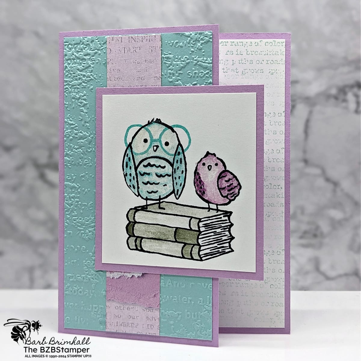 How to Make a Cute Handmade Greeting Card Quickly featuring 2 birds in blue and purple sitting on a pile of green books.  No sentiment but pretty papers and embossed background.