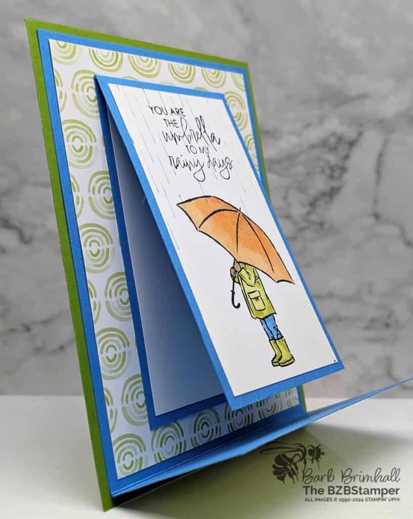 Fun Fold with the Umbrella Days Stamp Set in blues, greens and oranges, with someone holding an umbrella and a "you are the umbrella to my rainy days" sentiment.