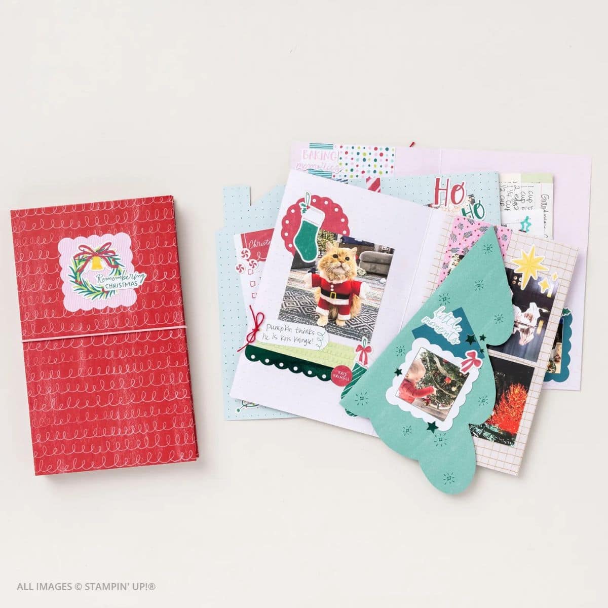 Photo of the Holiday Memories with the Remembering Christmas Kit, showing a completed red album and several decorated holiday scrapbook pages featuring photos, journaling, and festive embellishments like trees, stockings, and stars.