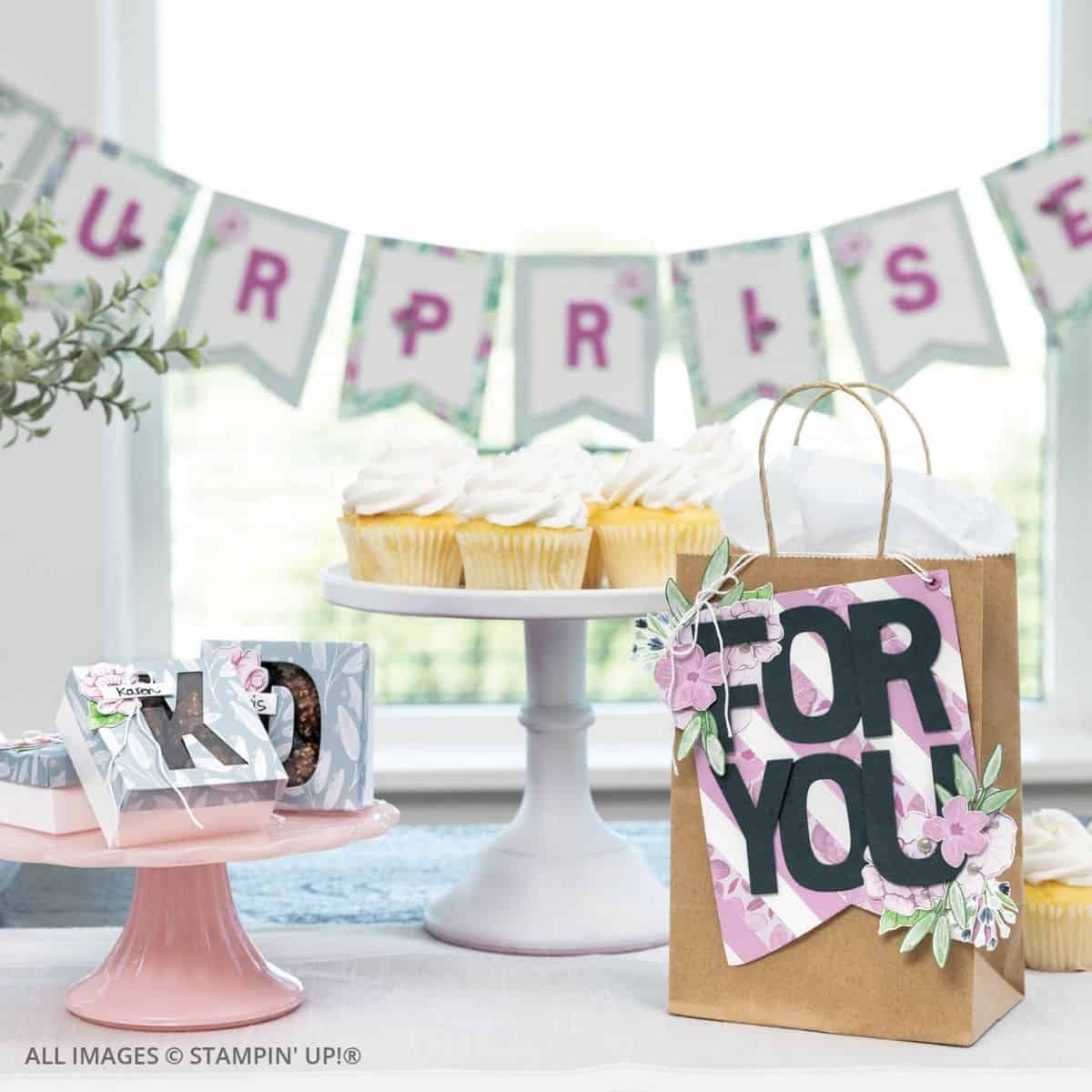 Building Relationships Through Cardmaking. A birthday party scene with a handmade “For You” gift bag, coordinating mini treat boxes, and a “Surprise” banner in soft pinks and greens. Cupcakes and paper-crafted décor add a personal handmade touch to the celebration.