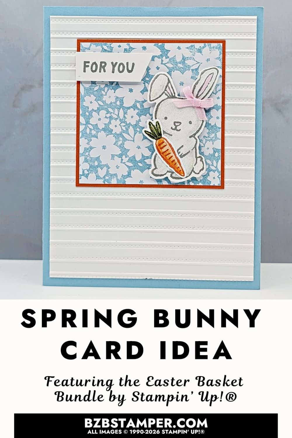 Spring All Occasion Card Using the Easter Basket Bundle is a handmade greeting card with a soft light blue base and a textured white panel featuring subtle horizontal stripes. A layered square focal panel includes a light blue floral pattern framed in orange. A small bunny holding a carrot sits on the panel, finished with a pale pink bow. A short sentiment banner appears at the top, creating a cheerful springtime feel.